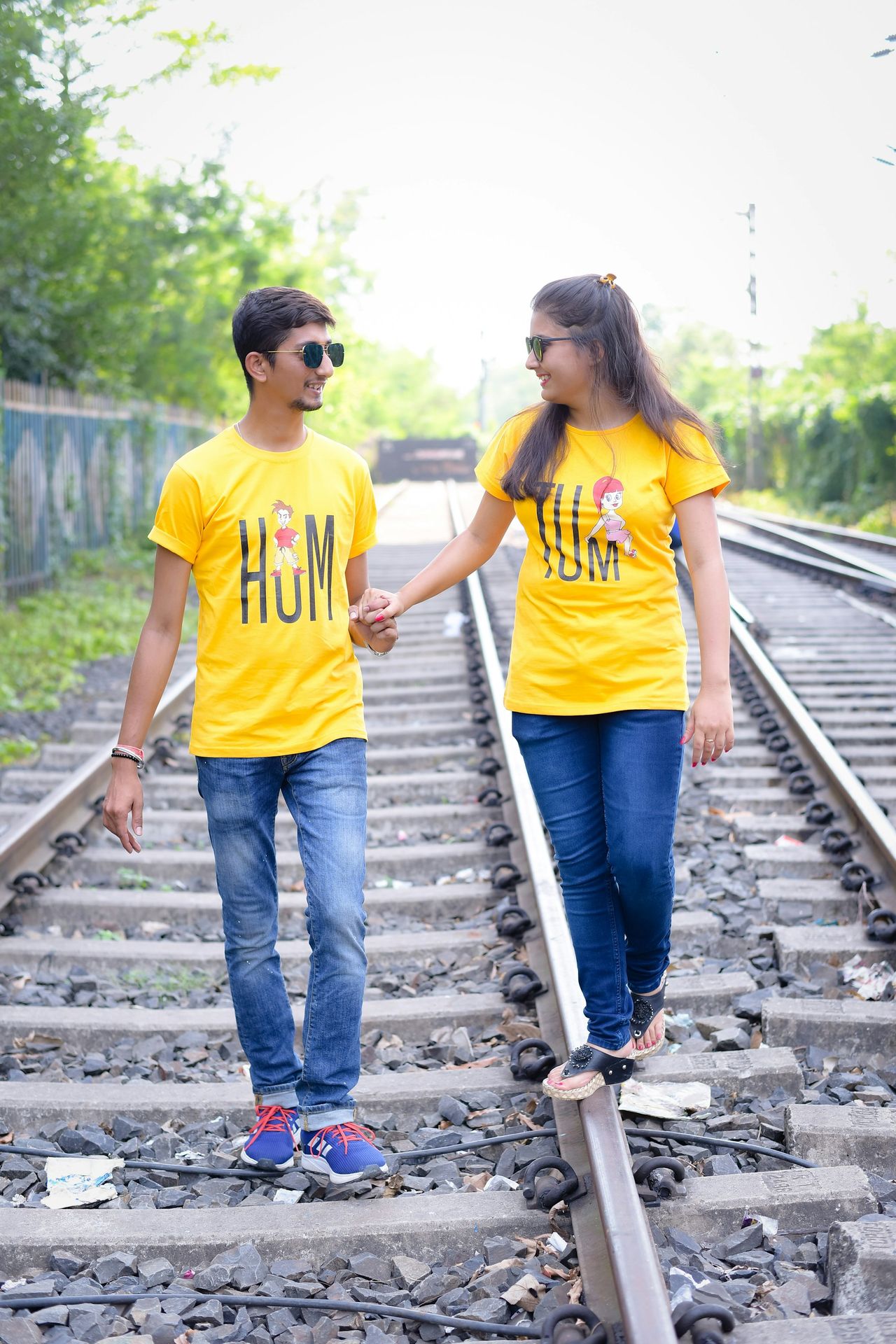 A man and a woman walking on railroad tracks